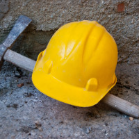 A yellow hard hat and hammer resting on the ground